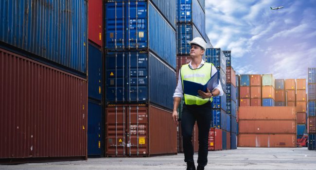 Foreman holding document, walking and checking the containers box from cargo ship for export and import Foreman holding document, walking and checking the containers box from cargo ship for export and import