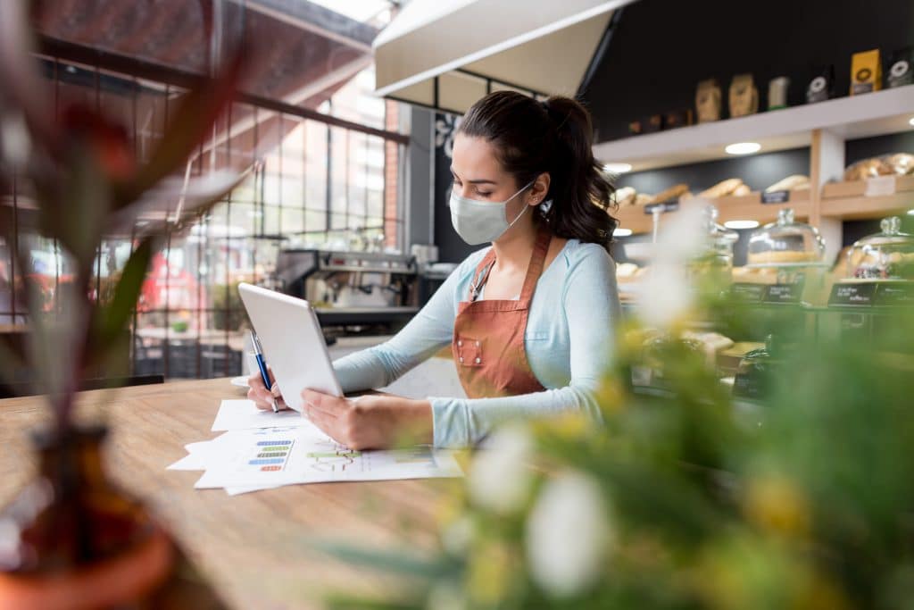 Woman wearing a facemask while doing the books at a restaurant